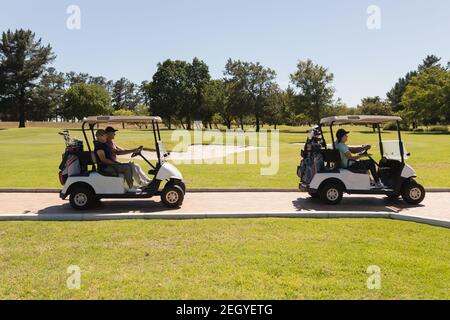 Deux couples de personnes âgées du caucase conduisant une voiturette de golf sur le parcours de golf parler et sourire Banque D'Images