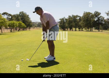 Femme caucasienne senior tenant un club de golf se préparant pour le tir sur le vert Banque D'Images