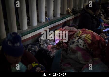 Tijuana, Mexique. 19 février 2021. Une jeune fille regarde un téléphone cellulaire alors que des dizaines de migrants dorment à côté de l'Institut national des migrations, près du poste frontière d'El Chaparral. Après avoir changé de direction en matière de politique migratoire, le gouvernement américain autorise une fois de plus les demandeurs d'asile de l'autre côté de la frontière. À compter de vendredi, les premiers requérants devraient arriver aux États-Unis pour leurs audiences et seront autorisés à rester dans le pays pour la durée de leur procédure. Credit: dpa Picture Alliance/Alay Live News Banque D'Images