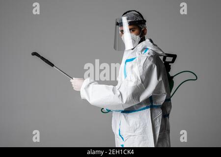 Prise de vue en profil d'un homme médique dans un hazmat convient de santizing avec un spray isolé sur fond blanc Banque D'Images