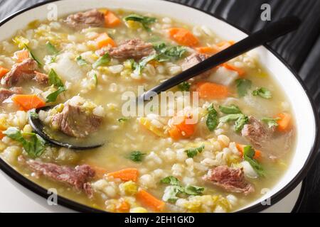 Savoureux bouillon Scotch Rich rempli de morceaux de légumes de la taille d'une morsure et d'agneau tendre dans l'assiette sur la table. Horizontale Banque D'Images