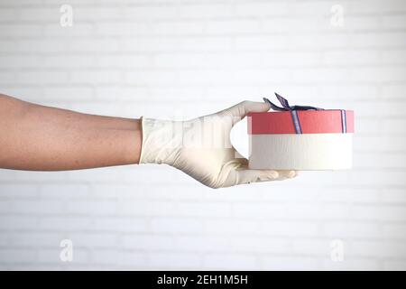 main de sexe masculin dans un gant médical bleu donne un cadeau. Banque D'Images