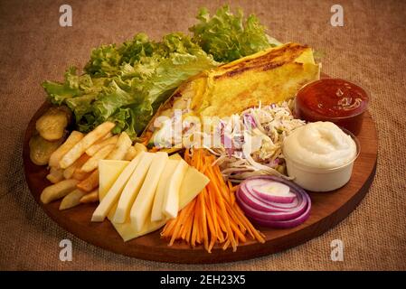 Shawarma végétarien avec légumes et fromage sur une planche à découper en bois. Banque D'Images