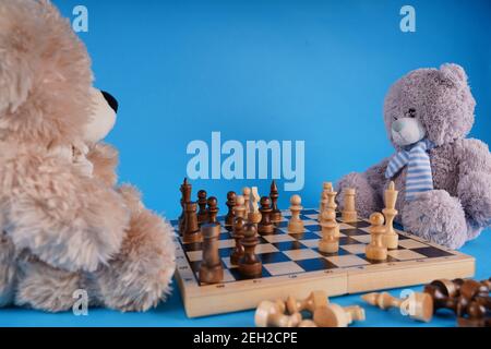 Gros plan sur les ours en peluche avec des pièces d'échecs sur l'échiquier. Jouets en peluche qui jouent aux échecs sur fond bleu Banque D'Images