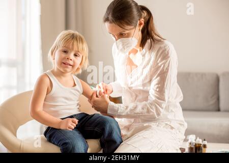 Petit enfant, garçon blond, injection dans la salle de consultation à partir de la pédiatrie, vaccination annuelle. Banque D'Images