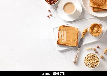 Pâte d'arachides et toasts croustillants sur fond blanc pour un petit déjeuner sain. Concept de nutrition saine. Vue de dessus. Banque D'Images
