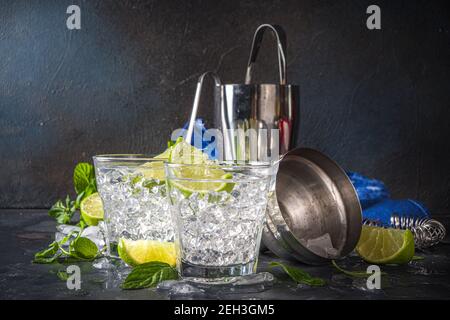 Cocktail d'été paloma, vodka lime, mojito ou tonique de gin avec coin de lime et glace écrasée dans les rochers, deux verres à boisson alcoolisée froide sur le backgroun noir Banque D'Images