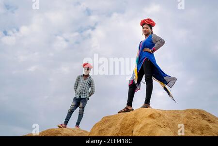 Belle, jeune femme gyesy pleurant rouge turband et des vêtements traditionnels debout sur une dune de sable dans le désert près de Pushkar, Rajasthan, Inde. Banque D'Images