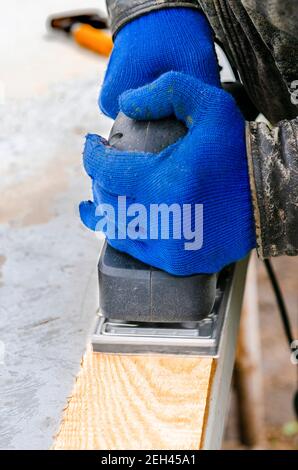 Utilisation d'une machine à meuler. Les mains des hommes en gants bleus fonctionnent avec des outils électriques Banque D'Images