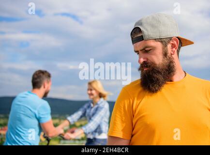 Hipster homme se sent seule en couple derrière lui. Pas de chance la vie romantique. Guy des profils toujours célibataire alors que les amis vie de famille heureuse. Hipster visage triste en face de couple dans l'amour. Romantique pas dans sa vie. Banque D'Images