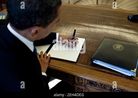 Le président Barack Obama écrit à son bureau dans le Bureau ovale, le 3 mars 2009. Banque D'Images