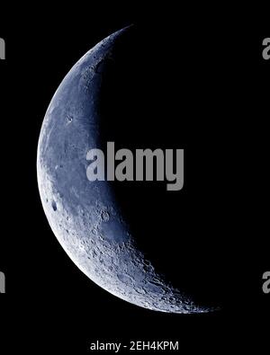 Lune en croissant avec détail cratère sur ciel bleu. Banque D'Images