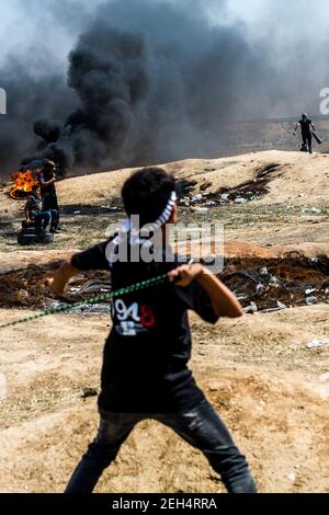 Un manifestant palestinien utilise un coup de feu pour lancer des pierres contre les forces israéliennes lors de manifestations à la frontière orientale de la ville de Gaza avec Israël. Les tensions sont vives le long de la frontière entre Gaza et Israël après plus d'un mois de manifestations de masse hebdomadaires près de la barrière qui a tué 50 manifestants palestiniens et blessé plus de 1,700 personnes par des tirs militaires israéliens. Les dirigeants du Hamas à Gaza ont promis que les marches se poursuivront jusqu'à la levée du blocus israélien de dix ans du territoire. Des manifestations sont également attendues les 14 et 15 mai, le jour où les Palestiniens marqueront Yawm an-Nakba ou 'Day of Disaste Banque D'Images