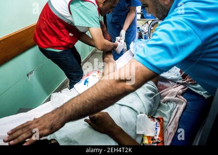 Mohamed Zeyad Al Zenaty, 19 ans, est soigné par des médecins à l'hôpital Al-Awda après avoir été blessé lors d'affrontements avec les forces israéliennes près de la frontière entre Gaza et Israël, dans la bande de Gaza (Palestine) - le 14 mai 2018 des soldats israéliens ont tué plus de 55 Palestiniens, dont 7 enfants, Et plus de 2,000 blessés, les manifestations à la frontière entre Gaza et Israël coïncidant avec l'ouverture controversée de l'ambassade américaine à Jérusalem. C'est le jour le plus meurtrier de la violence à Gaza depuis 2014. Les dirigeants du Hamas à Gaza ont promis que les marches se poursuivront jusqu'au blocus israélien d'une décennie du territoire Banque D'Images