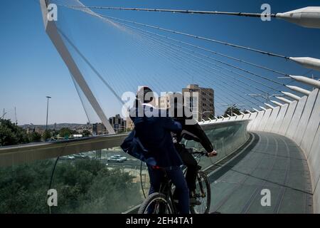 Deux juifs font le tour de leur vélo sur le pont des cordes. Celui-ci fait maintenant partie du paysage de Jérusalem. Avec ses câbles en acier reliant la structure à une sorte de mât, l'œuvre futuriste de l'architecte espagnol Santiago Calatrava permet au tramway de traverser une intersection très fréquentée à Jérusalem, sur la route menant à tel Aviv. Une passerelle avec garde-corps en verre adjacente au tramway a été prévue pour les piétons. 17 mai 2018. Jérusalem. Israël. Banque D'Images