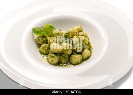 Gnocchi al pesto de Gênes, recette italienne traditionnelle faite de basilic frais, huile d'olive, pignons. Dans un plat blanc isolé sur blanc Banque D'Images