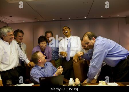 Le président Barack Obama rit des aides à bord d'Air Force One en route vers Singapour, le 14 novembre 2009. Banque D'Images