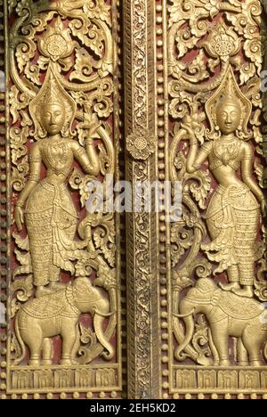 Asie, Laos, Luang Prabang, Wat Xieng Thong temple porte ornée sculpture détail représentant les danseurs traditionnels et les éléphants Banque D'Images