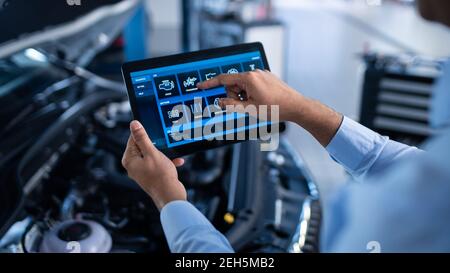 Car Service Manager ou Mechanic utilise une tablette avec un logiciel de diagnostic interactif futuriste. Un spécialiste inspecte le véhicule dans l'ordre Banque D'Images