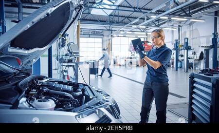 Femme Mechanic utilise une tablette avec un logiciel de diagnostic de réalité augmentée. Un spécialiste inspecte la voiture pour la trouver cassée Banque D'Images