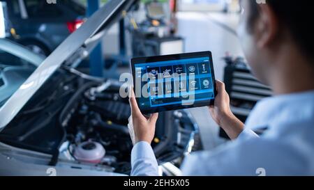 Car Service Manager ou Mechanic utilise une tablette avec un logiciel de diagnostic interactif futuriste. Un spécialiste inspecte le véhicule dans l'ordre Banque D'Images