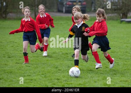 Groupe de jeunes filles footballeurs/joueurs de football en compétition pour le ballon lors d'une compétition interscolaire entre filles de football/football. Banque D'Images