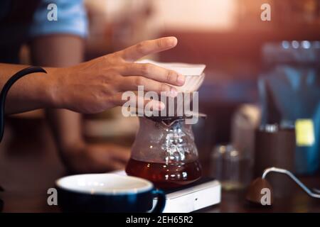 Barista mesure le goutte-à-goutte du café avec une tasse en verre Banque D'Images