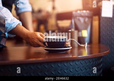 Barista serving cup of coffee on the table Stock Photo