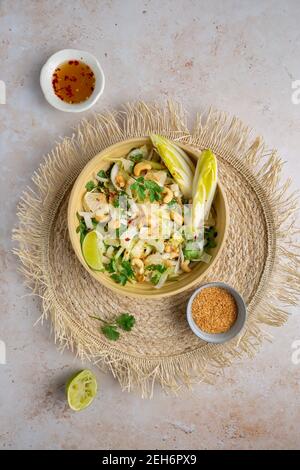 Vue de haut en bas d'une délicieuse salade de pomelo vegan style Bali sur un tapis naturel avec chicorée, concombre, noix de cajou, coriandre, noix de coco grillée et chi Banque D'Images