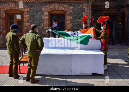 Srinagar, Inde. 19 février 2021. Les policiers ont déposé le drapeau indien sur le cercueil du défunt lors d'une cérémonie de pose de couronnes pour les deux policiers qui ont été tués lors d'une attaque militante à Srinagar. Plus tôt, trois militants et un policier ont été tués lors de deux rencontres séparées dans la vallée du Cachemire. Crédit : SOPA Images Limited/Alamy Live News Banque D'Images