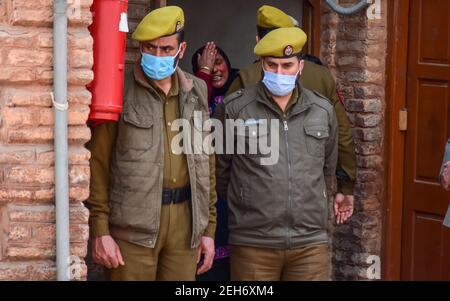 Srinagar, Inde. 19 février 2021. Un parent (c) se sourie à côté du cercueil du défunt lors d'une cérémonie de pose de couronnes pour les deux policiers qui ont été tués lors d'une attaque militante à Srinagar. Plus tôt, trois militants et un policier ont été tués lors de deux rencontres séparées dans la vallée du Cachemire. Crédit : SOPA Images Limited/Alamy Live News Banque D'Images