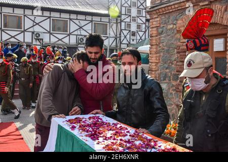 Srinagar, Inde. 19 février 2021. Un homme console un parent en deuil du défunt lors d'une cérémonie de pose de couronnes pour les deux policiers qui ont été tués lors d'une attaque militante à Srinagar. Plus tôt, trois militants et un policier ont été tués lors de deux rencontres séparées dans la vallée du Cachemire. Crédit : SOPA Images Limited/Alamy Live News Banque D'Images