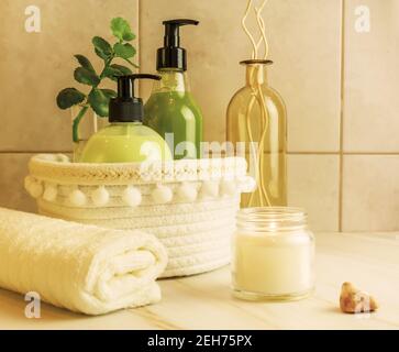 Concept de spa à la maison. Une table dans la salle de bains avec des cosmétiques, des accessoires, une serviette et une bougie parfumée éclairée. Spa détente rituels de baignade. Temps moi Banque D'Images