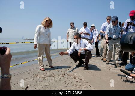 Le président Barack Obama et le président de la paroisse de Lafourche, Charlotte Randolf, sont partis, inspectent une boule de goudron en regard de l'effet de la marée noire de BP sur la plage de Fourchon à Port Fourchon, en Louisiane, le 28 mai 2010. Banque D'Images