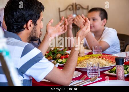 Arabe famille musulmane priant pour dieu avant de manger l'iftar Banque D'Images