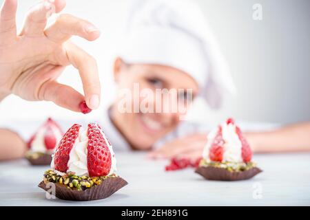 cupcakes fraise en premier plan, flou de fond chef femme Banque D'Images