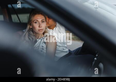 Homme allant embrasser la femme tout en étant assis dans la voiture avec place pour votre texte. Un couple heureux en voiture Banque D'Images