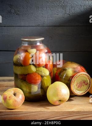 Sur une étagère dans le sous-sol se trouvent deux bocaux en verre avec des tomates en conserve, des concombres et des poivrons. Scellé avec un couvercle étanche. Vue de face, espace de copie. Banque D'Images