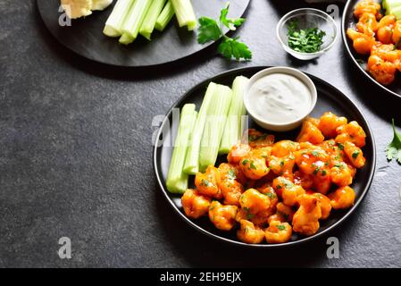 Ailes de buffle de chou-fleur avec céleri et sauce sur plaque sur fond de pierre noire avec espace libre pour le texte. Alimentation saine, nourriture à base de plantes concep Banque D'Images