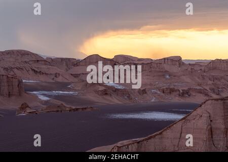 Tempête avec beaucoup de pluie venant au désert de LUT, Iran, dans l'heure d'or. Les nuages de Stormcloud se rassemblent tandis que l'horizon brille au soleil couchant. Bizzare Banque D'Images