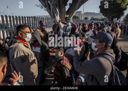 Tijuana, Mexique. 19 février 2021. Les migrants portant un masque attendent le passage frontalier « El Chaparral ». Suite à l'annonce du changement d'orientation de la politique migratoire des États-Unis, un grand nombre de migrants se sont rassemblés à la frontière entre le Mexique et les États-Unis dans le contexte de la pandémie de Corona. Crédit : Stringer/dpa/Alay Live News Banque D'Images