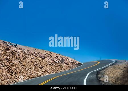 Conduite sur une route de montagne dans une courbe en épingle à cheveux avec dépose à un côté et juste le ciel qui s'affiche au-dessus du Ligne d'arbre sur Pikes Peak Colorado Banque D'Images