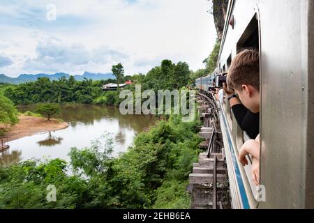 Train roulant au-dessus de la construction en bois le long de la rivière Kwai à Kanchanaburi, en Thaïlande. Sur le chemin de la célèbre rivière Kwai Bridge. Touristes lookin Banque D'Images