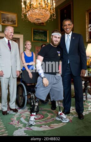 Le vice-président Joe Biden observe le président Barack Obama en photo avec le maître Taylor Morris dans la salle verte de la Maison Blanche, le 26 juillet 2012. Le Président a présenté un coeur pourpre à Morris, qui participait à une visite de la Maison Blanche avec d'autres guerriers blessés et leurs familles. Banque D'Images