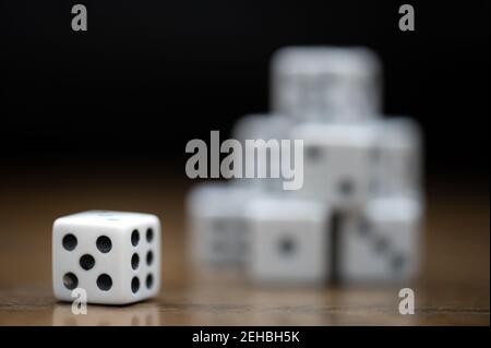 Dés montrant un cinq et un six avec une pile de dés en arrière-plan sur une table en bois Banque D'Images