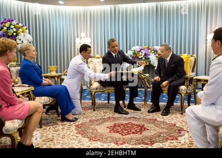 Le président Barack Obama présente un cadeau au roi Bhumibol Adulyadej de Thaïlande lors de sa réunion à l'hôpital Siriraj de Bangkok, Thaïlande, le 18 novembre 2012. Le président Obama a présenté un album photo contenant des photos du roi avec les présidents américains et les premières dames datant du président Eisenhower. L'ambassadeur des États-Unis en Thaïlande Kristie Kenney et la secrétaire d'État Hillary Rodham Clinton sont assis à gauche. Banque D'Images