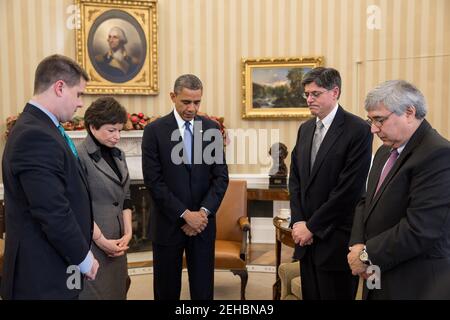 Le président Barack Obama fait une pause au cours d'une réunion pour observer un moment de silence dans le Bureau ovale à 9 h 30 le 21 décembre 2012, en souvenir des 20 enfants et six adultes tués dans le tir de l'école élémentaire Sandy Hook à Newtown, dans le Connecticut, le 14 décembre. Parmi les membres du président, de gauche à droite, on trouve : le directeur des communications, Dan Pfeiffer; la conseillère principale, Valerie Jarrett; le chef d'état-major, Jack Lew; et Pete Rouse, conseiller du président. Banque D'Images