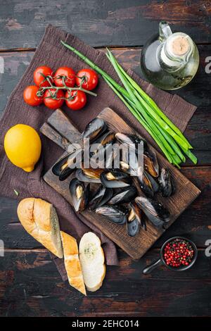 Moules ragoût dans le vin blanc et les herbes, sur la planche à découper en bois, sur le fond de la table en bois sombre, sur le dessus de l'appartement avec vue Banque D'Images