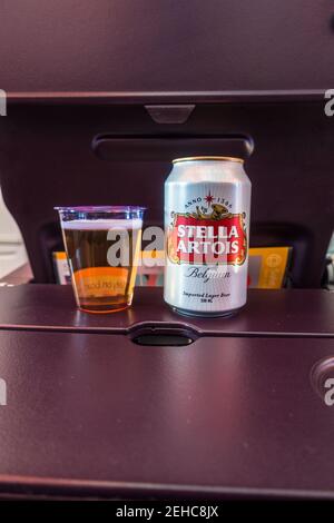 Bière dans une tasse à côté de la bière peut sur un table de plateau de siège passager Banque D'Images