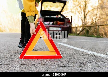 Personne non reconnaissable en train de poser un triangle d'avertissement sur le panneau de signalisation autoroute Banque D'Images